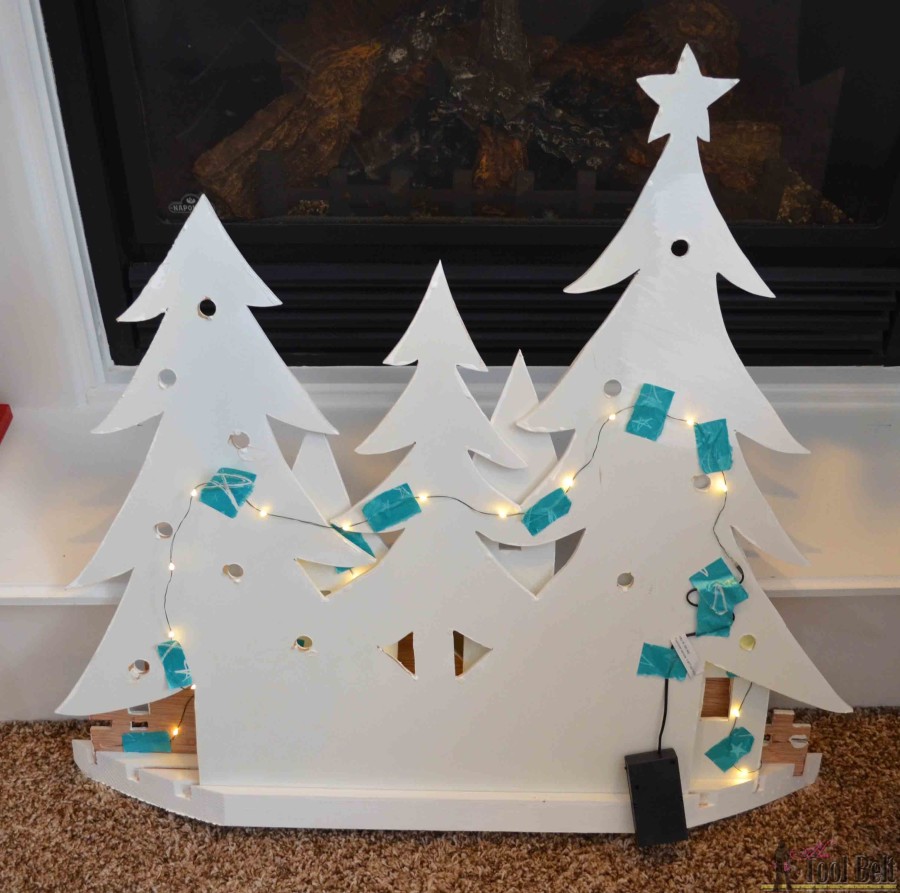 Tape lights to the back. DIY Pottery Barn Kid's inspired Christmas village silhouette.